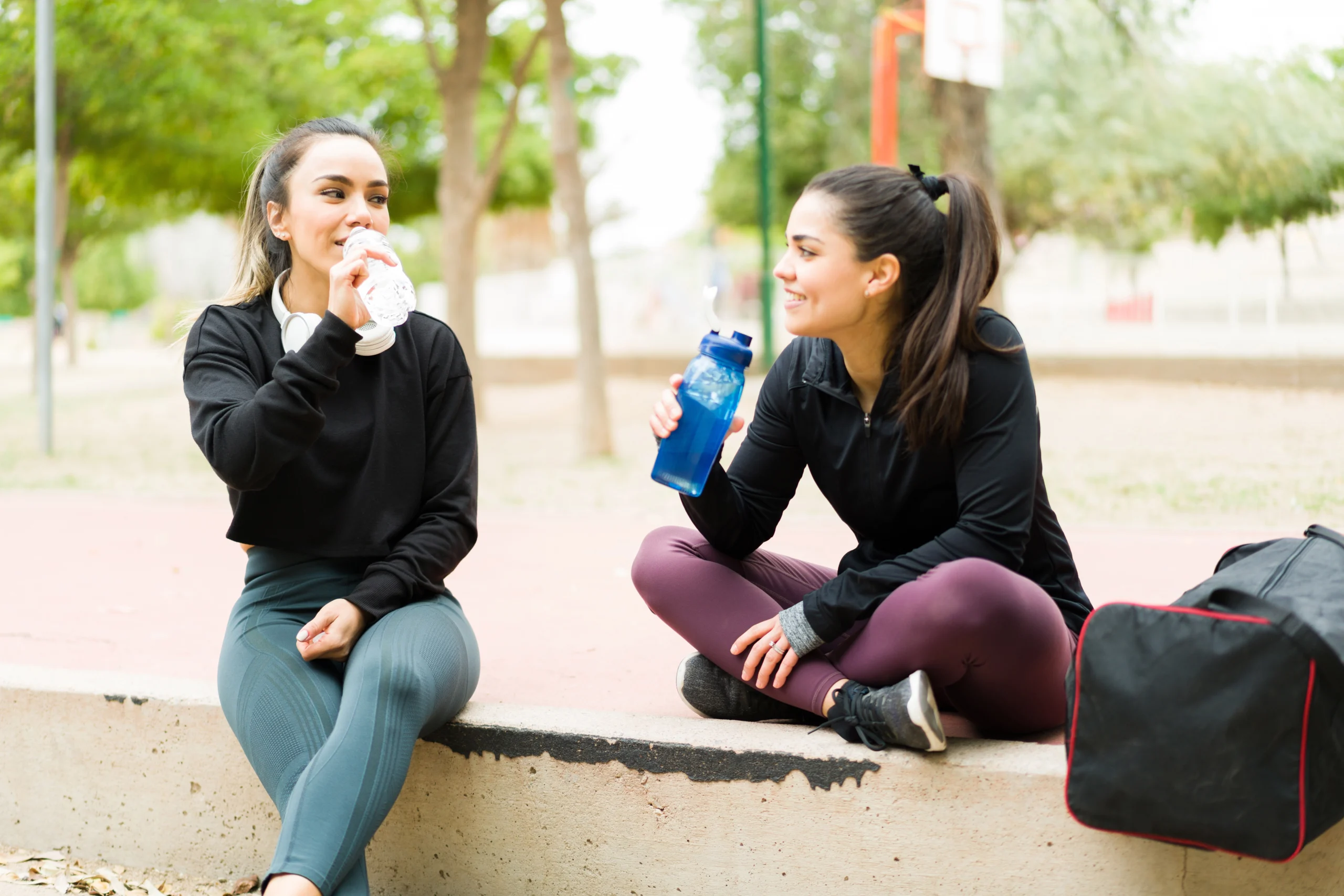 dwie ubrane na sportowo koleżanki piją wodę i rozmawiają
