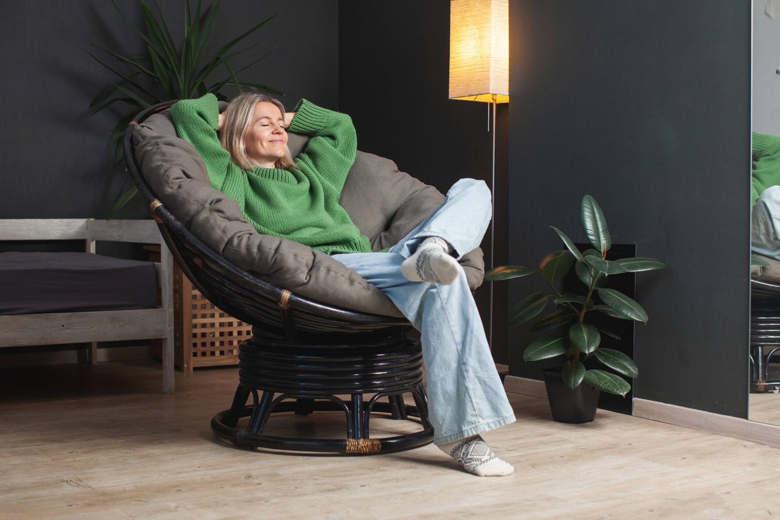 kobieta w domu relaksuje się na fotelu przy kwiatku